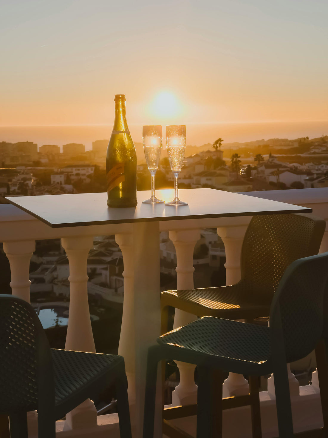 Champagne bottle and glasses on a terrace at sunset — illustrating Fragrenza's edit of the best fragrances for spring evenings.