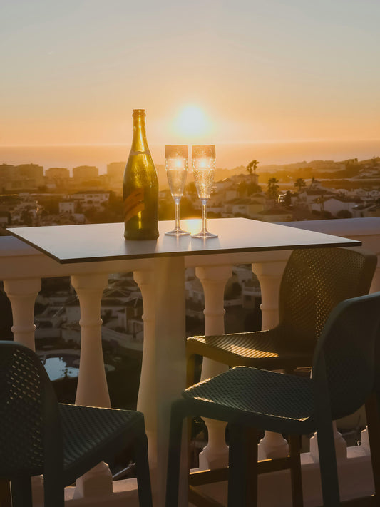 Champagne bottle and glasses on a terrace at sunset — illustrating Fragrenza's edit of the best fragrances for spring evenings.