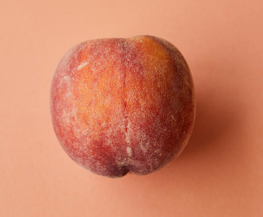 Fresh ripe peach in soft light — the velvety, sun-warmed fruit defining 2026 peach perfumery
