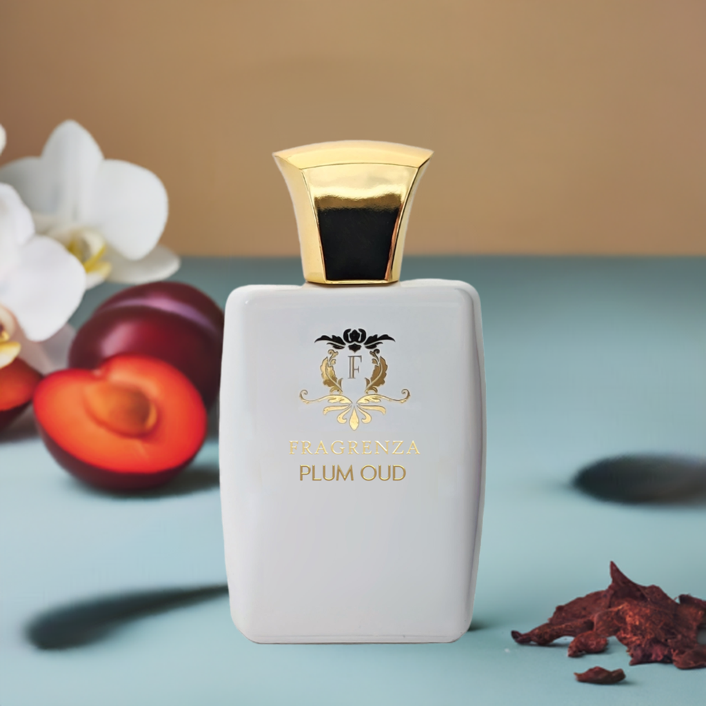 Perfume bottle labeled 'Fragrenza Plum Oud' with gold cap on a light blue surface with fruits and flowers.